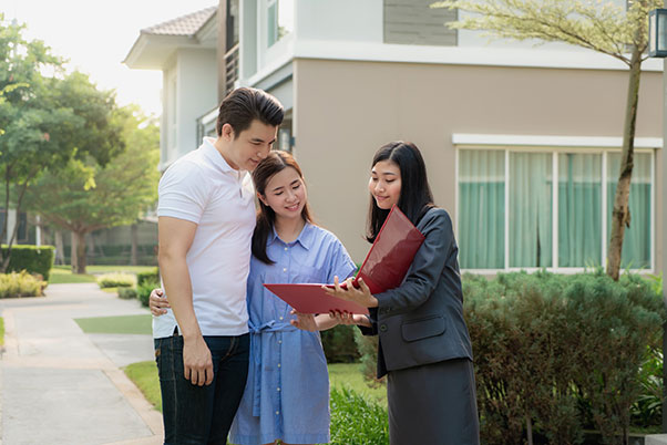 Jeune agente immobilière sans diplôme montrant le dossier d’une habitation à un jeune couple