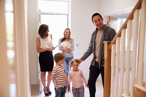 Jeune agente immobilière en reconversion faisant visiter une maison à une famille avec trois enfants